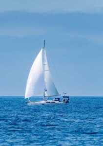 white sailboat full sails blue sky blue ocean